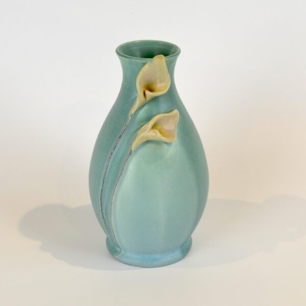 This image shows our Calla Lily Vase in aqua. The vase has an hour glass shape. Two calla lilies are featured near the top of the vase and their steams lead from the flowers to the base of the vase.